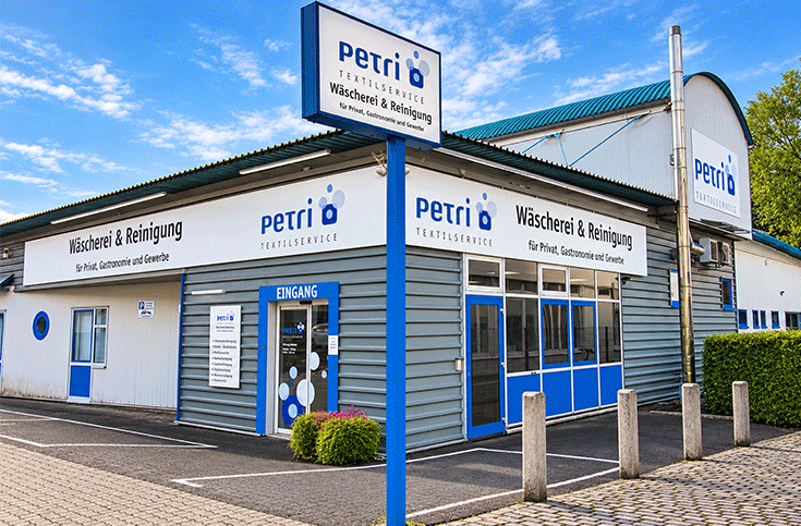 Außenansicht des Textilservice Petri – Wäscherei & Reinigung für Privat, Gastronomie und Gewerbe mit Eingang und Firmenschild