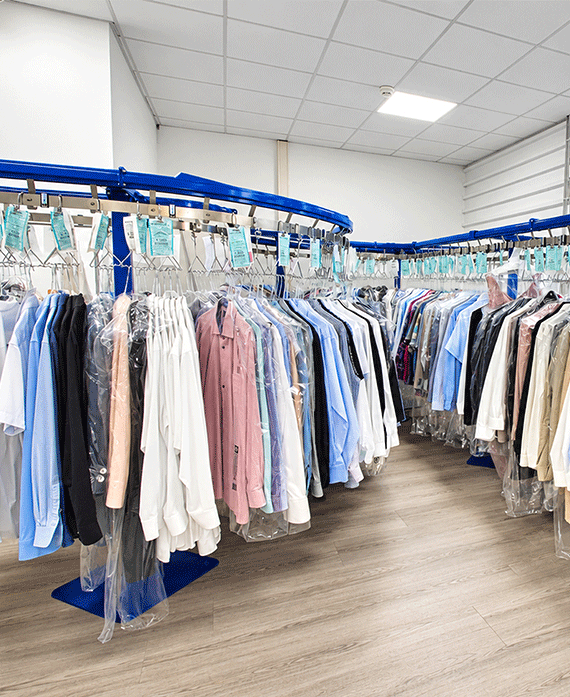TSP_Innenansicht_Eingangsbereich Innenansicht des Textilservice Petri mit gereinigter Kleidung auf Kleiderbügeln in Schutzfolie, bereit zur Abholung